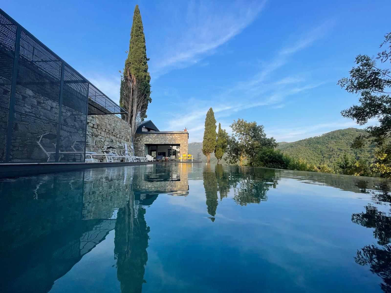 Casa Rufo — infinity pool reflecting cypress trees and Ligurian hills